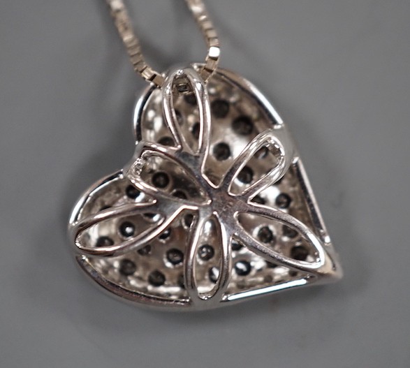 A modern 18ct white gold and pave set white and black diamond set heart shaped pendant, 16mm, on an 18ct white gold fine link chain, 45cm, gross weight 4.4 grams